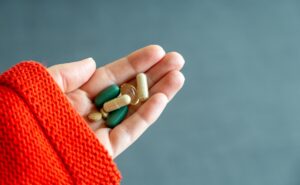 Hand holding a variety of gut health supplement capsules and pills.